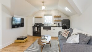 A modern kitchen with white cabinets, a black refrigerator, and a window above the sink. - The Russell House - Walk to Restaurants & Bars! (Nashville)
