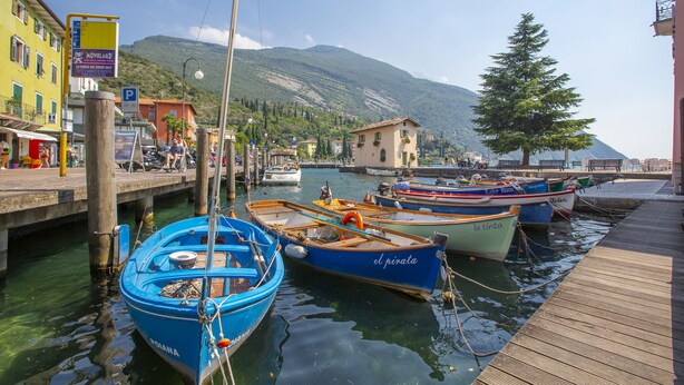Un puerto deportivo con barcos amarrados, un muelle de madera y edificios a lo largo de la costa.