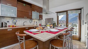 Una cocina con isla central, taburetes de bar y vistas a las montañas a través del ventanal.