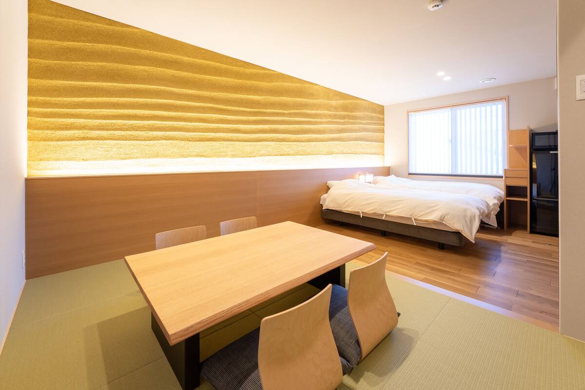 A modern bedroom with a bed, bedside table, and a large window.