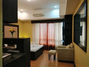 A hotel room with a bed, a desk, a chair, and a TV.
