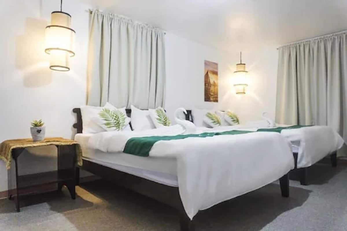 Une chambre d’hôtel avec un lit double, deux tables de chevet et deux lampes fixées au mur.