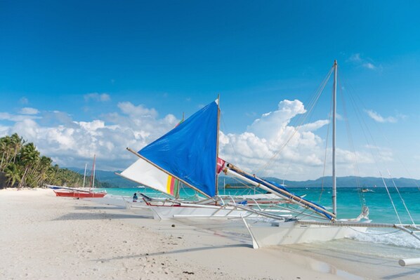 Ein Strand mit traditionellen Booten und blauem Himmel.