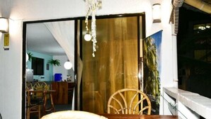 Une table à manger en bois ornée d’un volant de navire, un lustre et une vue sur une pièce comprenant un lit et une fenêtre.