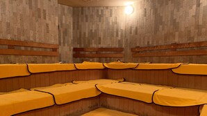 A sauna room with wooden benches and benches covered with yellow towels. - Funabashi Grand Sauna and Capsule Hotel - Caters to Men (Funabashi)