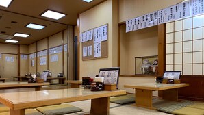 A traditional Japanese room with tatami mats, low tables, and calligraphy on the walls. - Funabashi Grand Sauna and Capsule Hotel - Caters to Men (Funabashi)