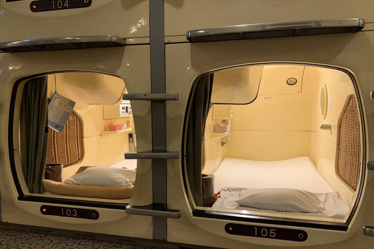 A train car with two sleeper compartments, each with a window, a bed, and a small shelf.
