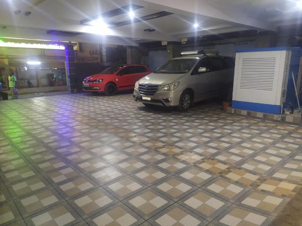 A parking garage with two cars parked, a tiled floor, and a ventilation unit.