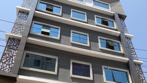 Un edificio de varios pisos con un diseño arquitectónico moderno, que cuenta con una serie de balcones y ventanas amplias.