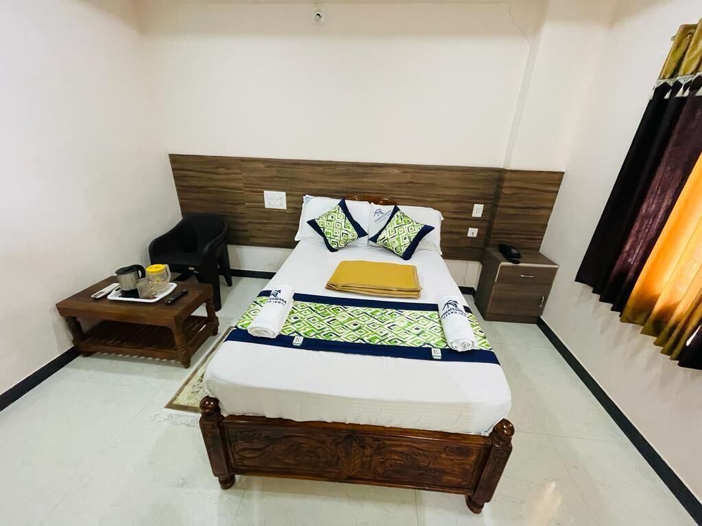 A neatly made bed with a wooden headboard, a bedside table with a lamp, and a wall-mounted curtain rod.