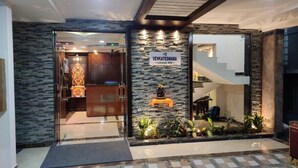 Una entrada de hotel con fachada de piedra, un mostrador de recepción y una escalera que conduce a los pisos superiores.