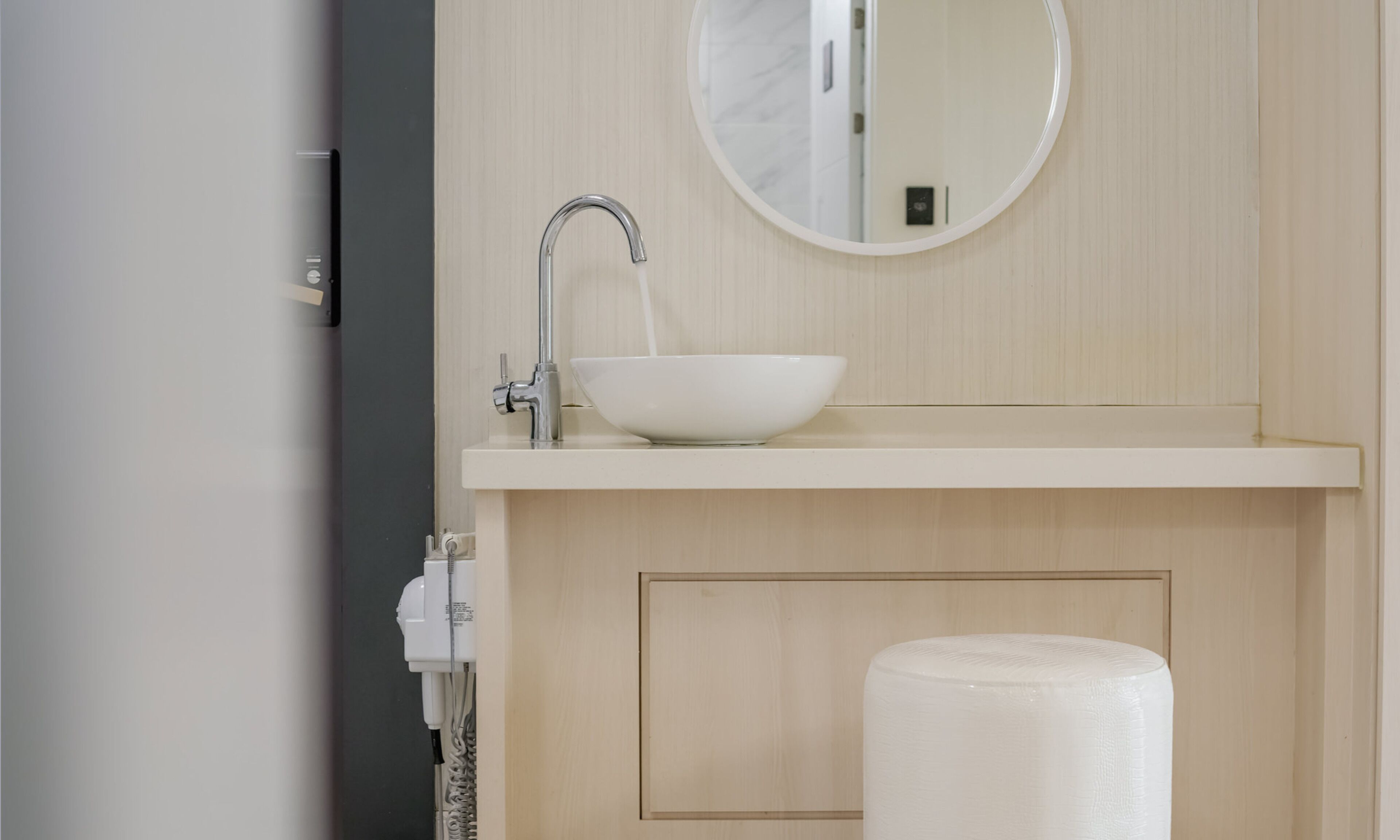 A bathroom with a white sink, a round mirror, and a toilet.