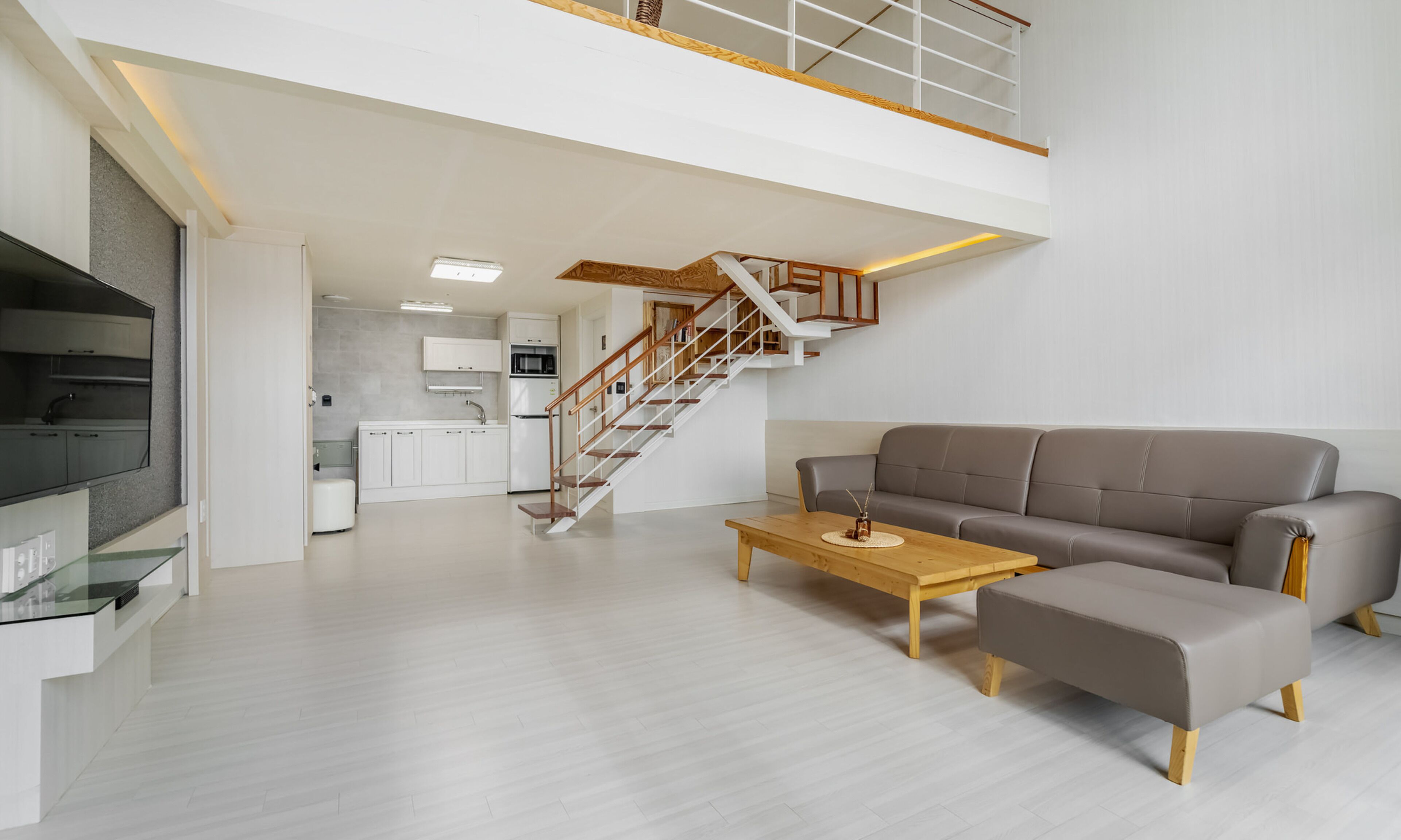 A spacious living area with a sofa, coffee table, and a staircase leading to an upper level.