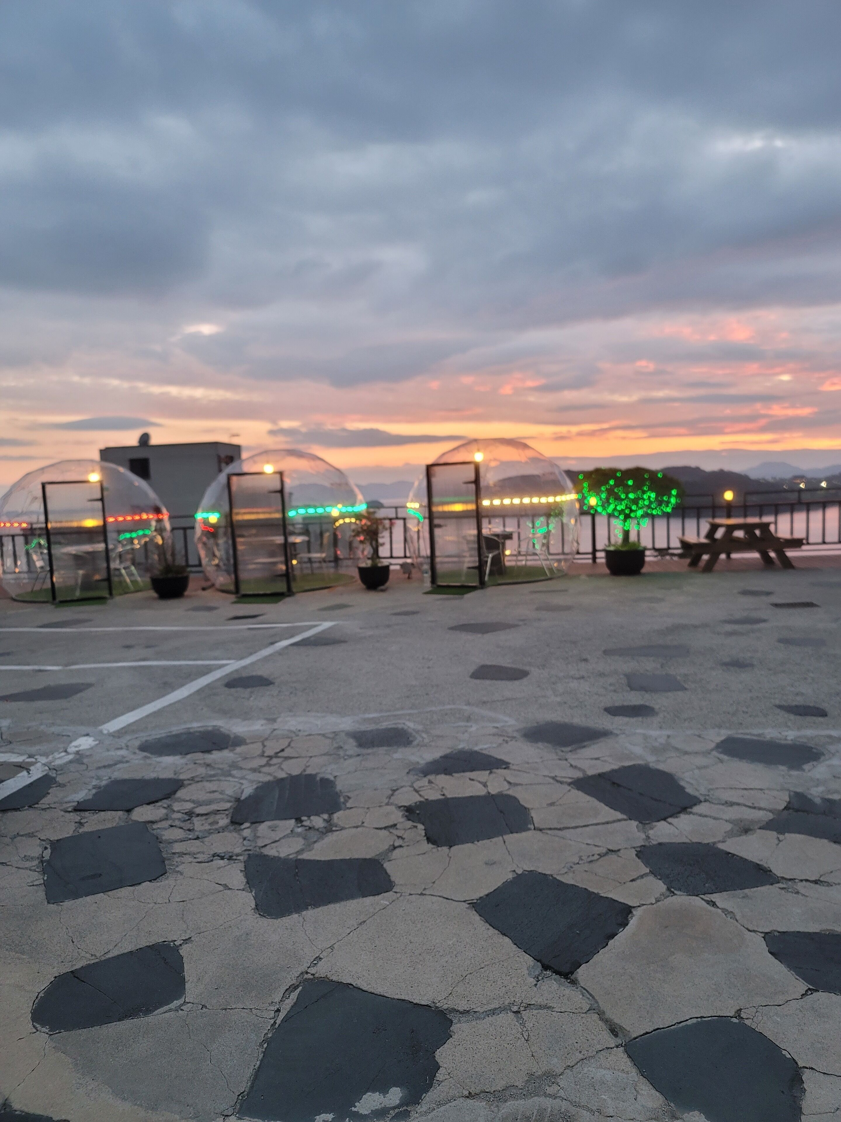 A rooftop terrace with transparent domes, a view of the sunset, and a paved floor.