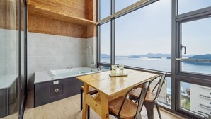 A modern kitchen with a large window, a wooden table, and a bathtub. - Yeosu Sunset Hostel and Pension (Yeosu)