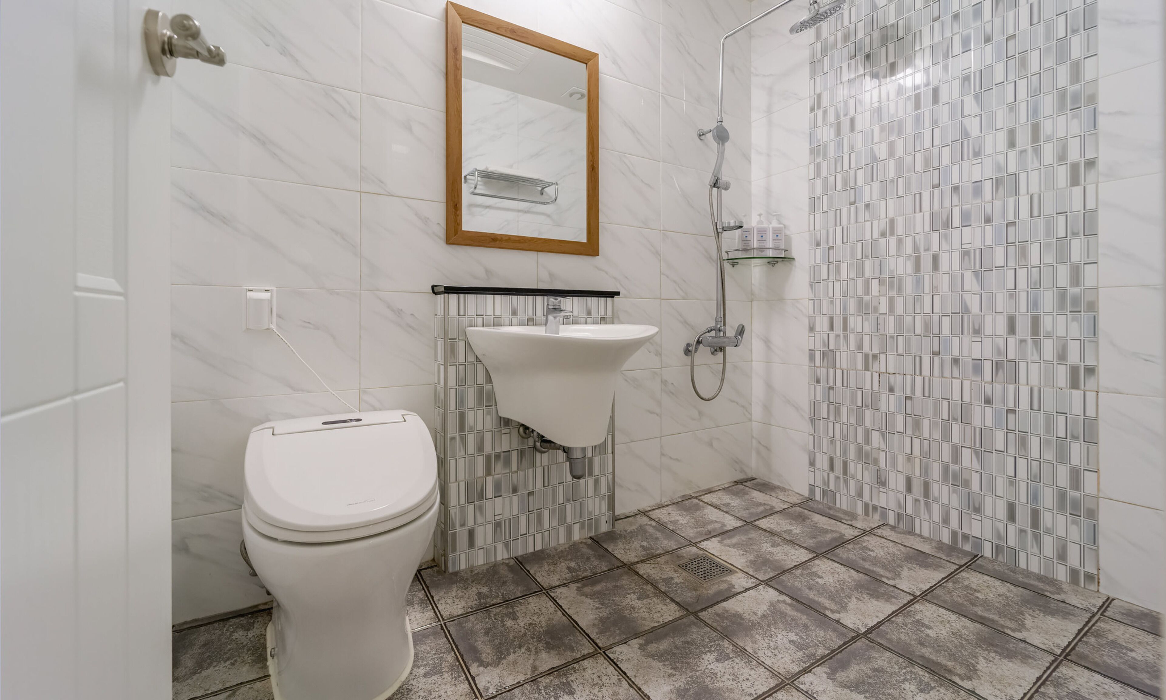 Een badkamer met toilet, wastafel en douche.