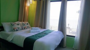 A hotel room with a bed, pillows, and a view of the sea.