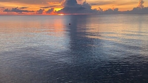 Rustig water weerspiegelt de ondergaande zon met een verre horizon.