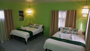 Une chambre d’hôtel avec deux lits, des murs verts et des rideaux.