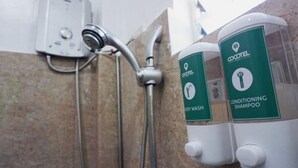 A shower with a handheld showerhead and two bottles of shampoo labeled 'COCCENTL'. - Oslob New Village by Cocotel (Oslob)