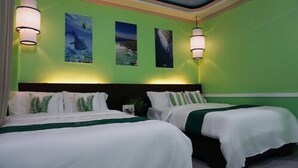 A hotel room with two beds, a green wall, and three framed pictures. - Oslob New Village by Cocotel (Oslob)