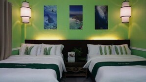 A hotel room with two beds, green walls, and three framed pictures on the wall. - Oslob New Village by Cocotel (Oslob)