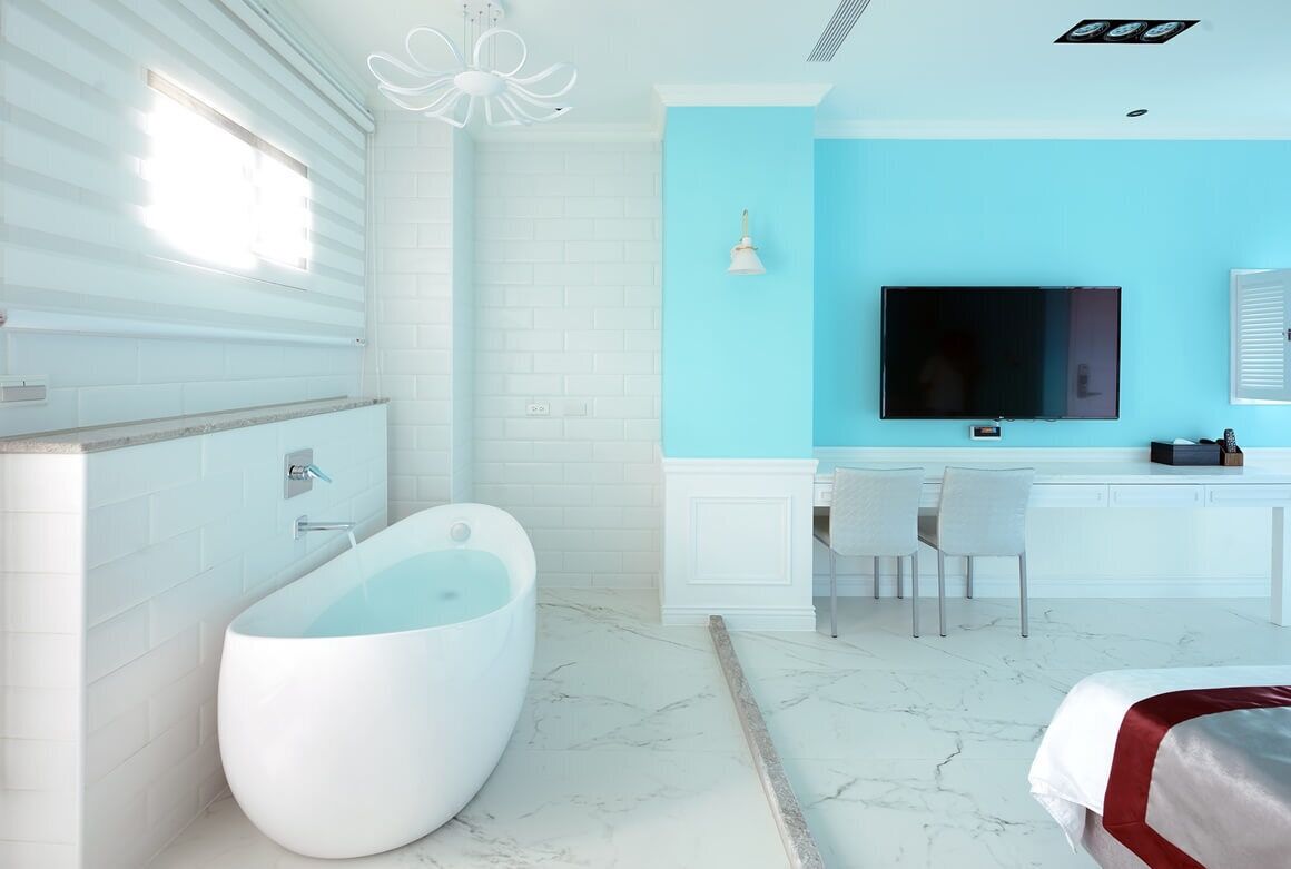 A modern bathroom with a freestanding bathtub, a vanity with a mirror, and a television mounted on the wall.