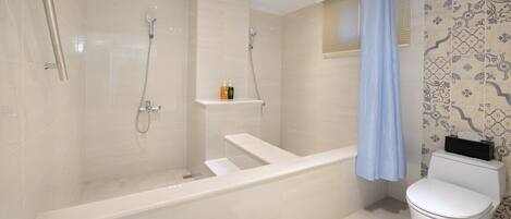 Een moderne badkamer met een badkuip, douche en toilet.