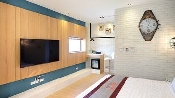Una habitación de hotel moderna con un televisor de pantalla plana grande, un panel de pared de madera, una pared decorativa de ladrillo, un reloj original y una cama con colcha roja y blanca.