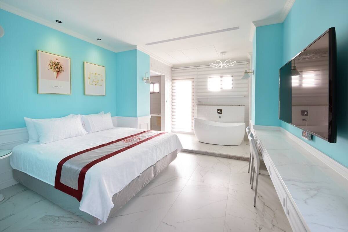 Una habitación de hotel moderna con una cama grande, un televisor y un baño con bañera.