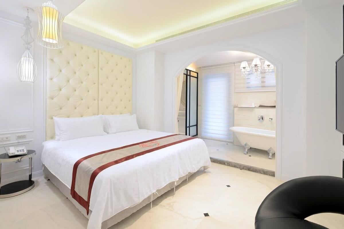 Una habitación de hotel moderna con una cama grande, baño separado con bañera y televisión.