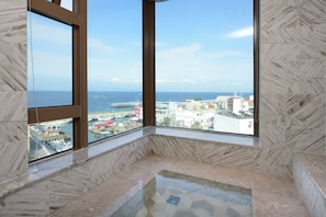 A room with large windows overlooking a marina and cityscape. - Hand in Hand INN (Liuqiu)