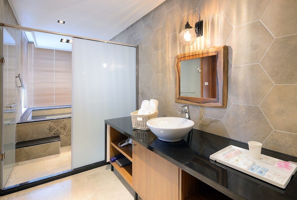 A modern bathroom with a glass shower enclosure, a white sink, and a wooden vanity.