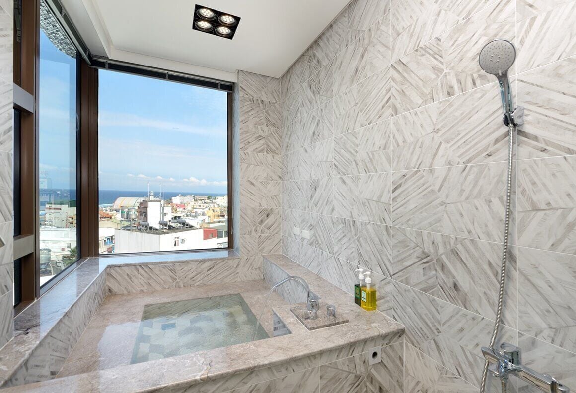 A bathroom with a large window, a bathtub, and a shower.