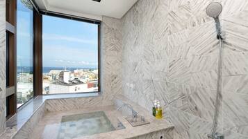 A bathroom with a large window, a bathtub, and a shower.
