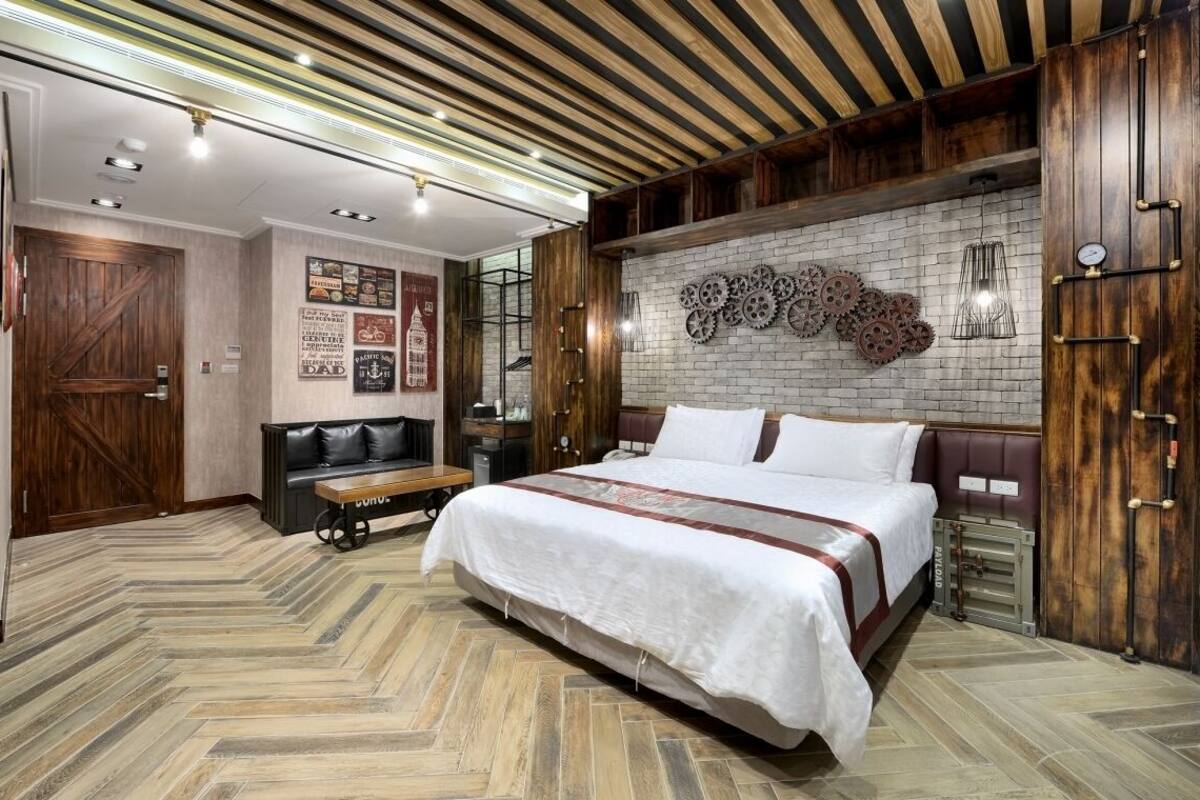 Un dormitorio con una cama grande, suelo de madera y una pared de ladrillo con engranajes.