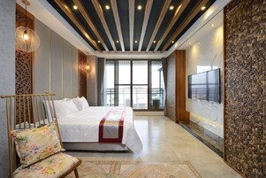 Habitación de hotel moderna con una cama grande, televisión y vistas a la ciudad.