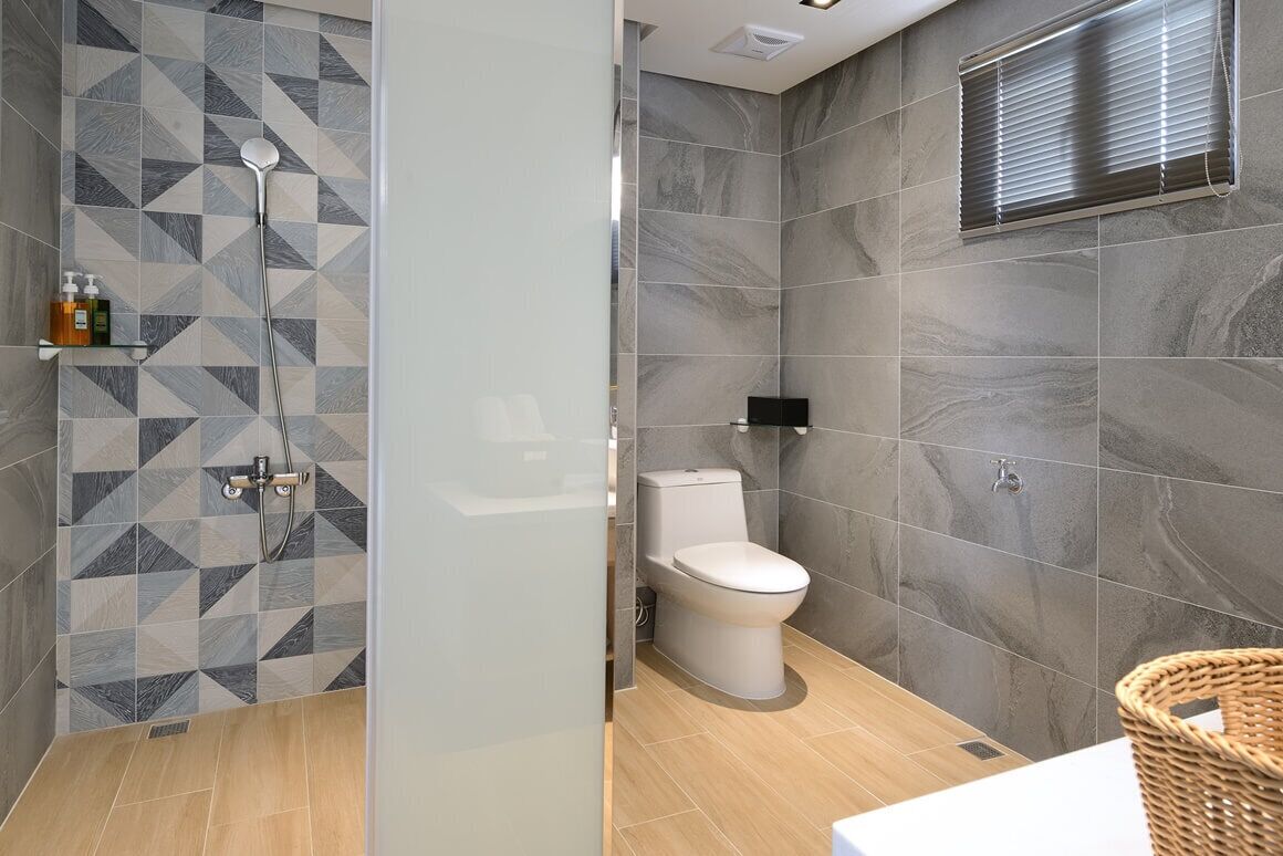 A modern bathroom with a shower, toilet, and a tiled wall with geometric patterns.