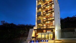 A multi-story hotel with a modern design, featuring balconies on each floor and a prominent entrance with a sign. - Hand in Hand INN (Liuqiu)