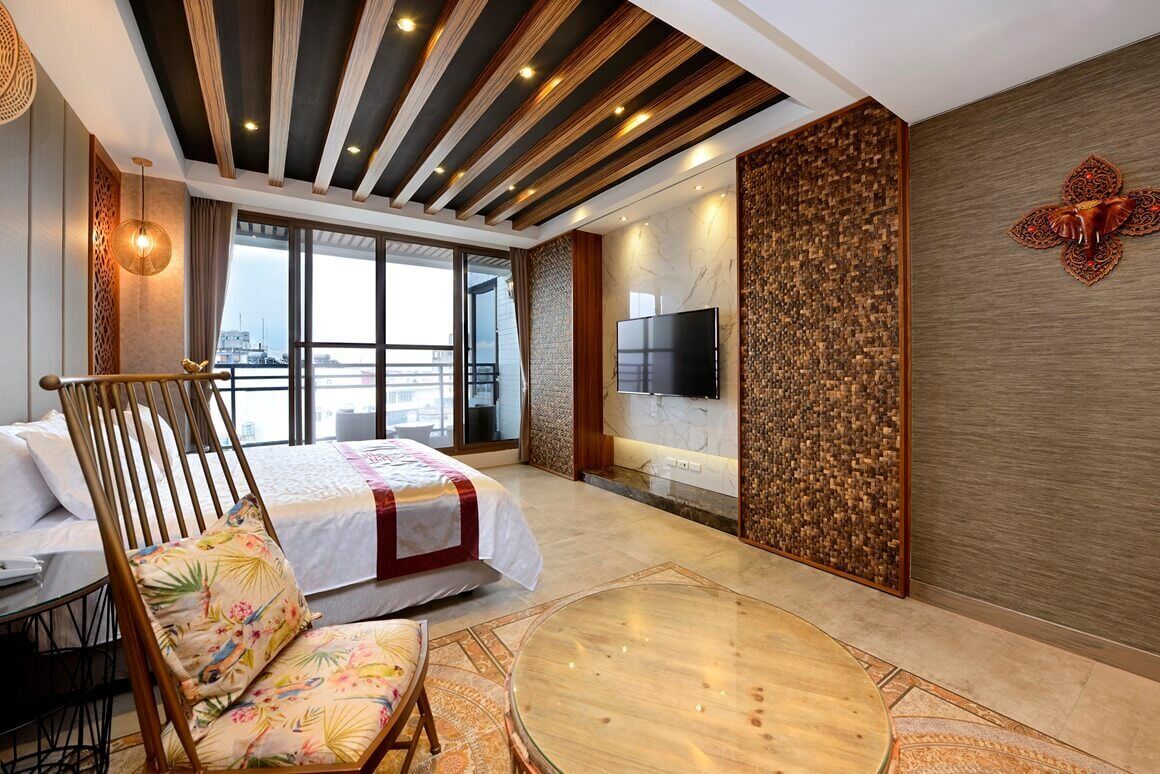 A modern hotel room with a large bed, a round glass table, a wooden chair, a TV, and a city view.