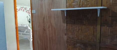 A room with a wooden door, a patterned wall, and a white shelf.