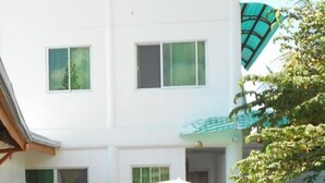 A white multi-story building with multiple windows and balconies. - Cronin Inn by Cocotel (Oslob)