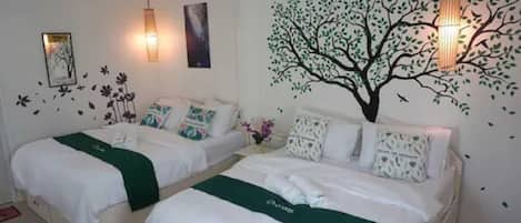 Habitación de hotel con dos camas, un mural de un árbol y pegatinas decorativas en la pared.