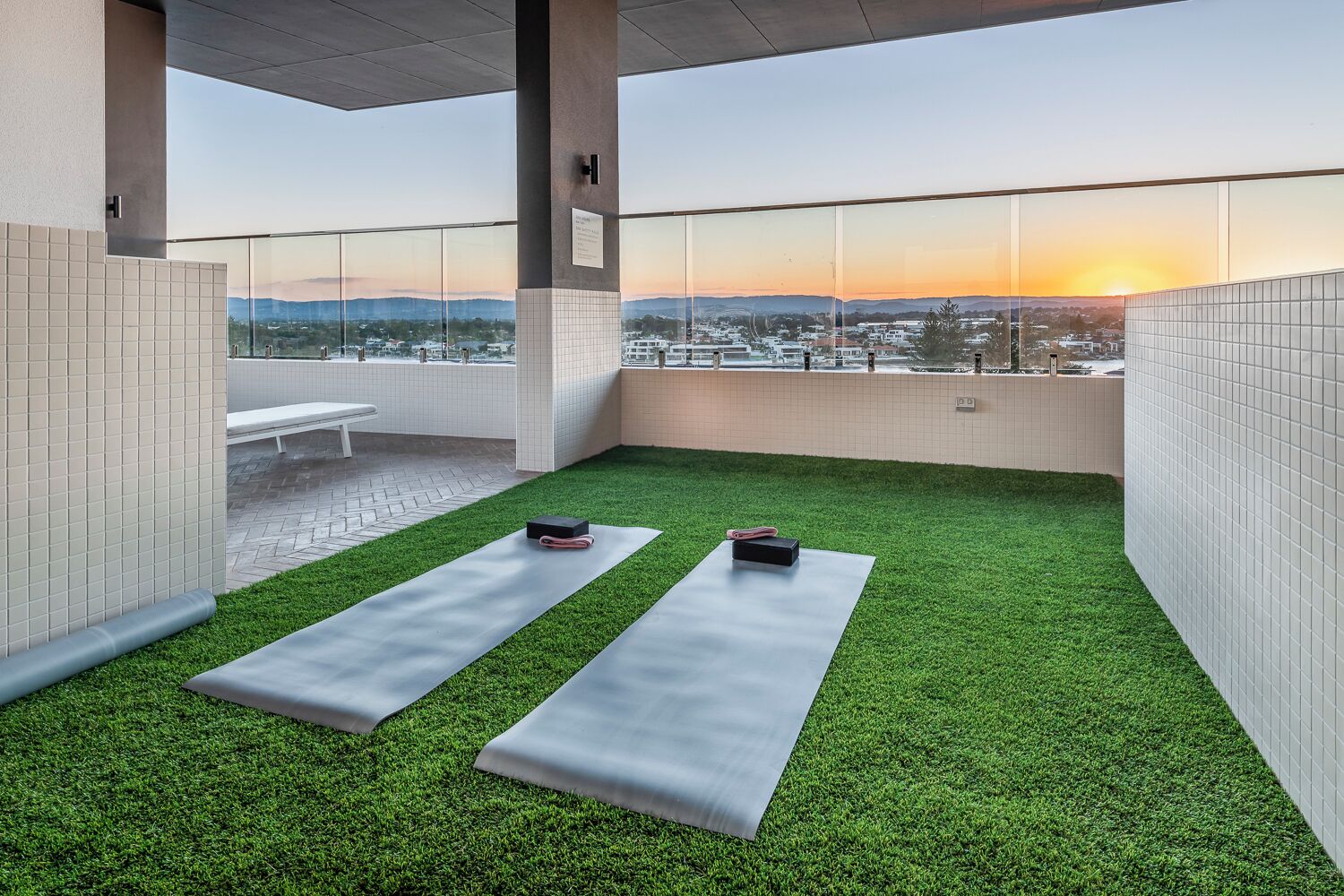 En takterrass med konstgräs, två yogamattor och träningsutrustning.