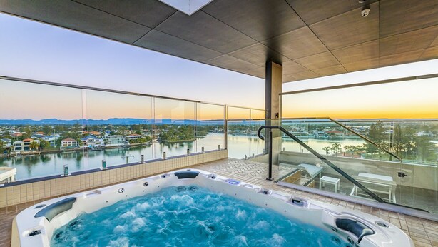 Uma banheira de hidromassagem em uma varanda com vista para um corpo de água e edifícios ao longe.