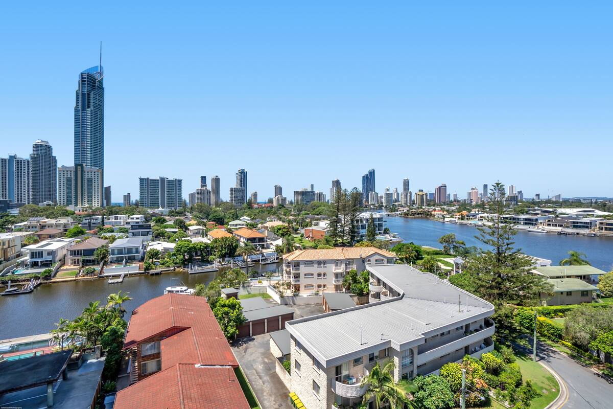 A high-rise building with a modern design, surrounded by residential buildings and a waterfront.