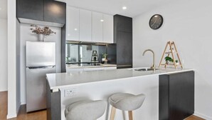 Uma cozinha moderna com ilha central, armários brancos e uma parede de destaque preta.