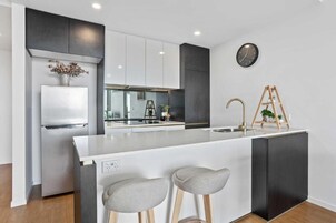 Una cocina moderna con una isla central, armarios blancos y una pared de acento negra.