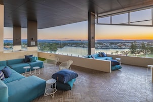 Un área de estar moderna con vistas a un río y al paisaje urbano al atardecer.