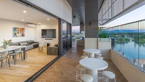 Um interior moderno com área de jantar, um conjunto de sofás e vista para um corpo d'água.